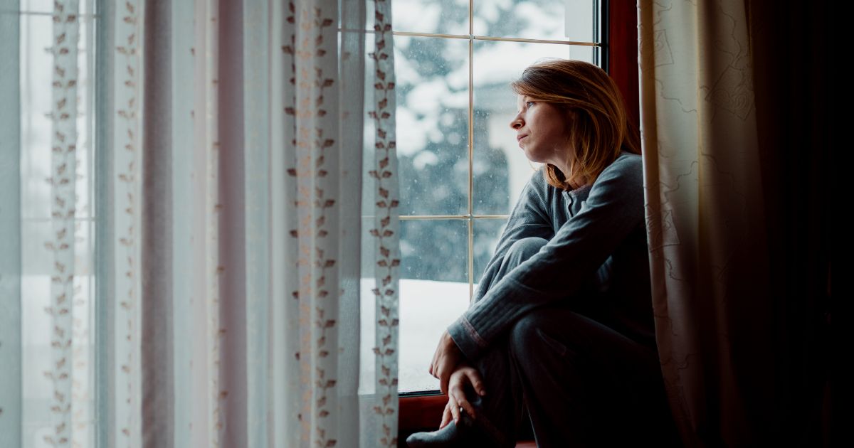 woman looking out window longingly