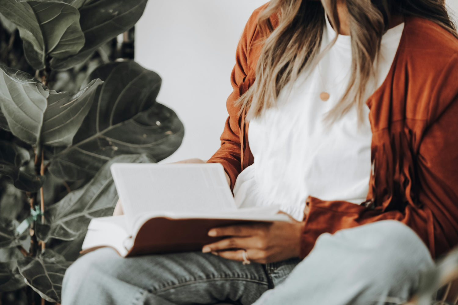 Woman with open book sitting by a plant