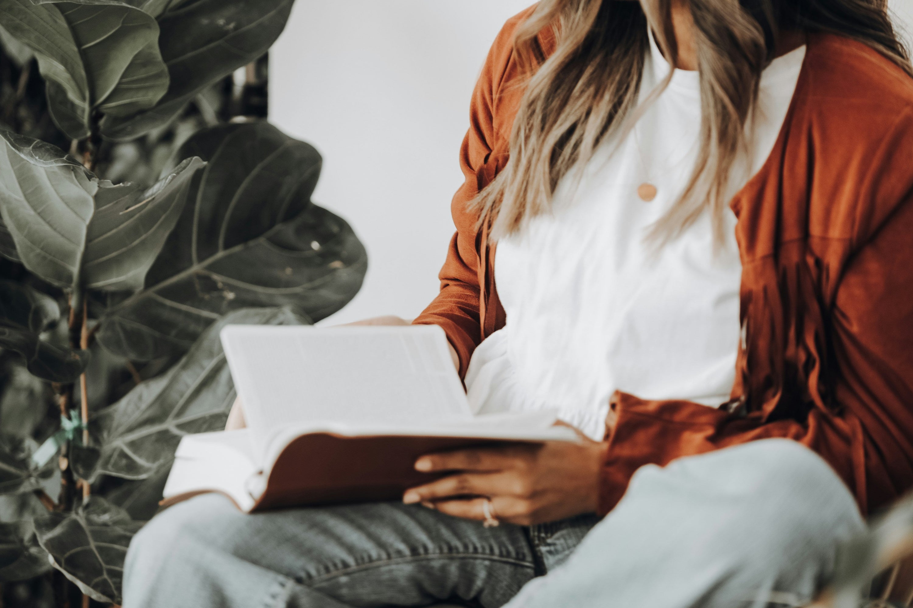 Woman with open book sitting by a plant